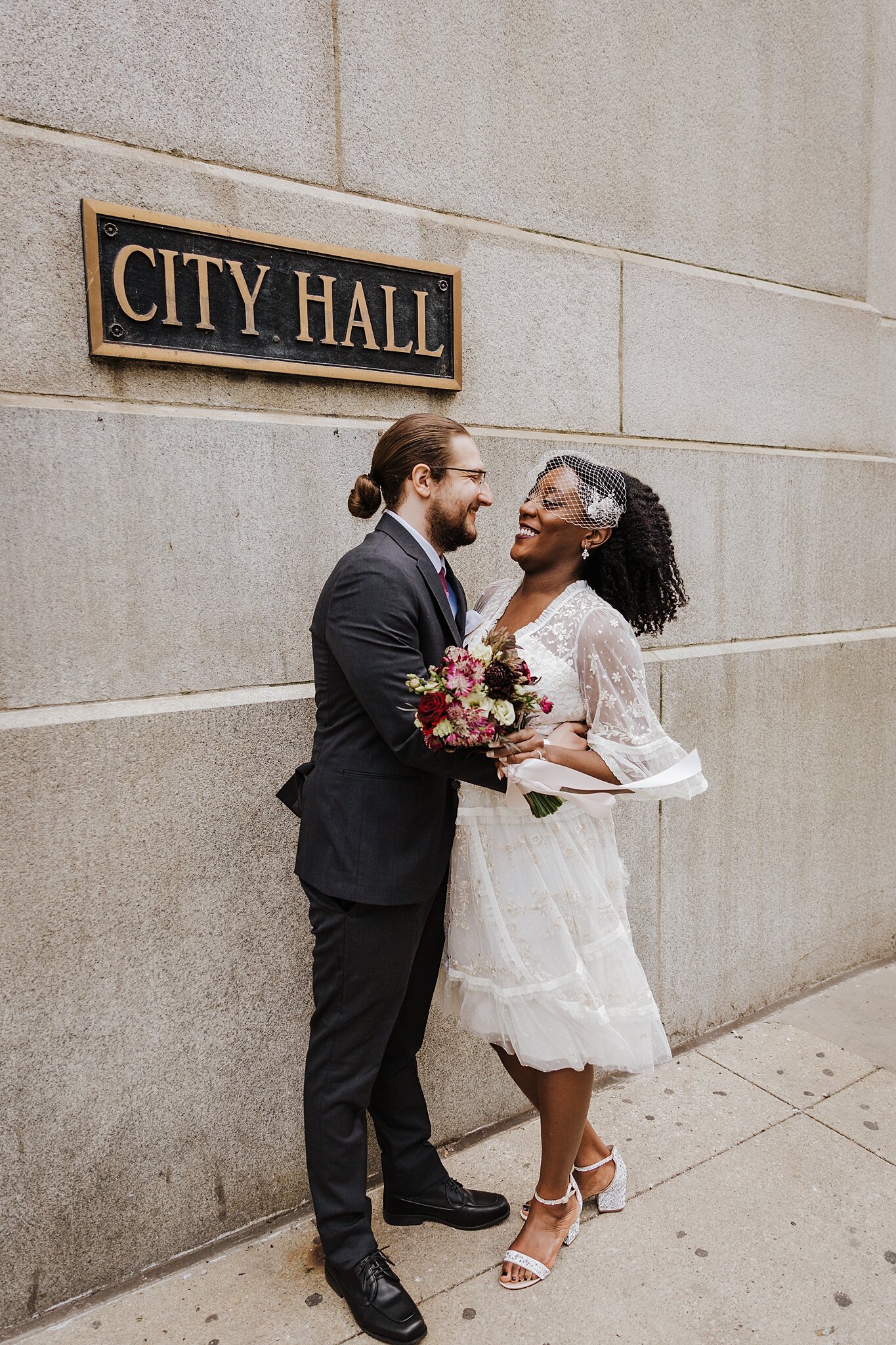 young biracial couple after their ceremony at Chicago's City Hall, standing in front of city hall sign