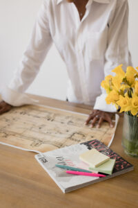 detail photo of a woman leaning on a desk and looking at architectural drawings
