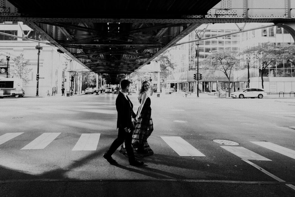 couple holding hands and walking under Lake Street L Romantic River North engagement session