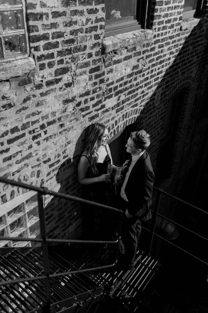 couple having drinks on fire escape Romantic River North engagement session